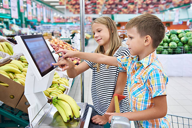 niño y niña comprando plátanos en la tienda - instrument of weight fotografías e imágenes de stock