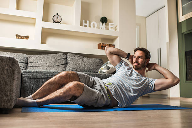 istock Young athletic man doing sit-ups in the living room. 614328432