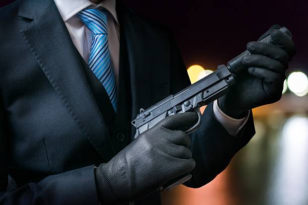 istock Killer holds gun with silencer in hands at night. 614330158