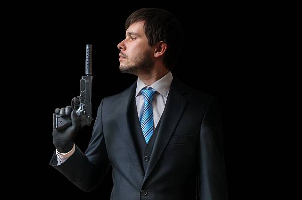 istock Spy holds pistol with silencer in hand on black background. 614330176