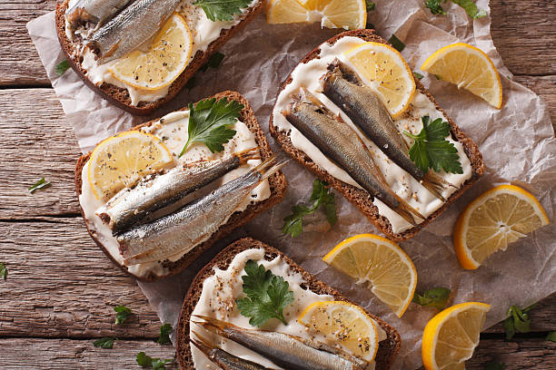 istock Toasts with sprats, cream cheese and lemon close-up. horizontal 614330378