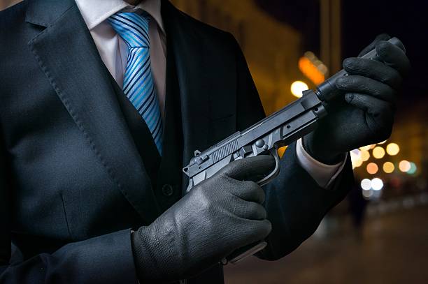 istock Hitman or assassin holds pistol with silencer in hands. 614330480