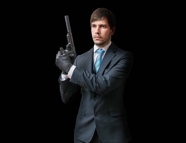 istock Main in suit holds pistol with silencer in hands. 614330606