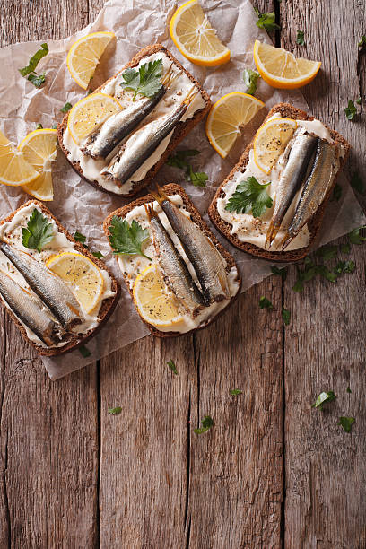 istock Sandwiches with sprats, cream cheese and lemon. vertical top view 614330790