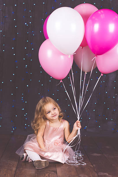 istock Little pretty girl in studio with pink balloons 614331002