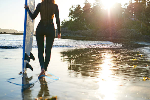 istock Strong beautiful young woman with surf on the beach 614332074