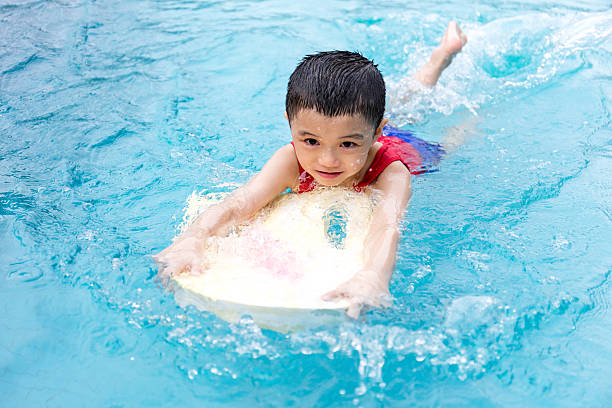 istock Asian Chinese Little Boy Swimming With Floating Board 614332750