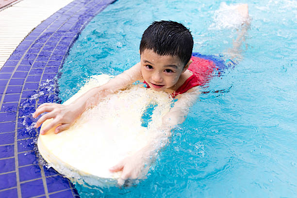 istock Asian Chinese Little Boy Swimming With Floating Board 614332974