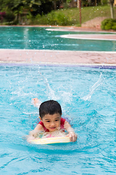 istock Asian Chinese Little Boy Swimming With Floating Board 614333082