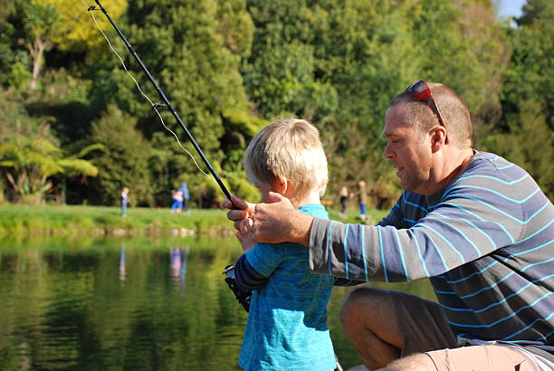 istock Father Teaches his Young Child how to Fish 614333104