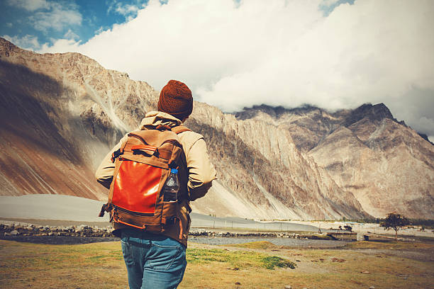 istock Back of young travel backpacker walking towards mountain 614333152