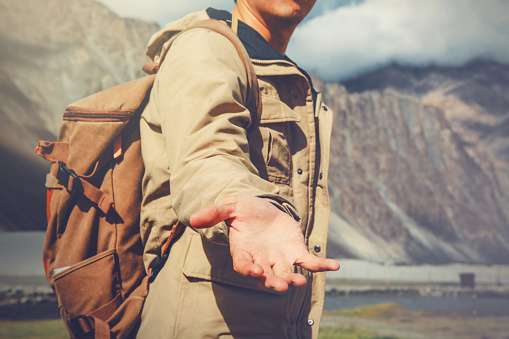 Joven hombre de viaje echando una mano en la montaña photo