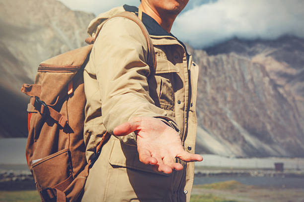 jeune homme de voyage donnant un coup de main dans la montagne - guising photos et images de collection