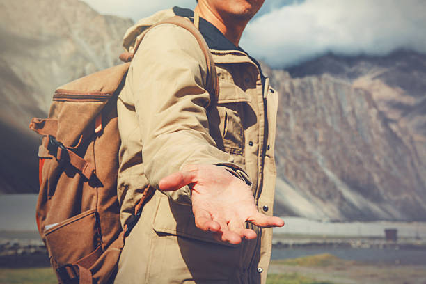 Young travel man lending a helping hand in mountain stock photo
