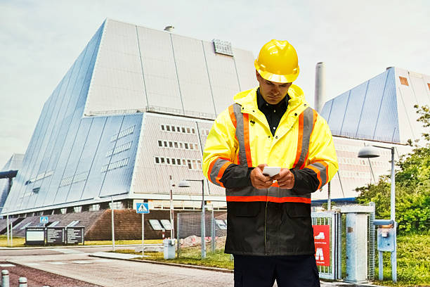 istock Worker using phone in front of power station 614334150