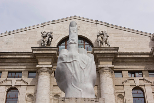 Milan, Italy - April 16, 2015: Close up of the controversial sculpture by Italian Maurizio Cattelan in front of  stock exchange building in Piazza Affari, Milan