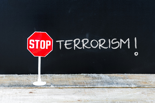 Mini STOP sign over chalkboard background and table, STOP TERRORISM concept