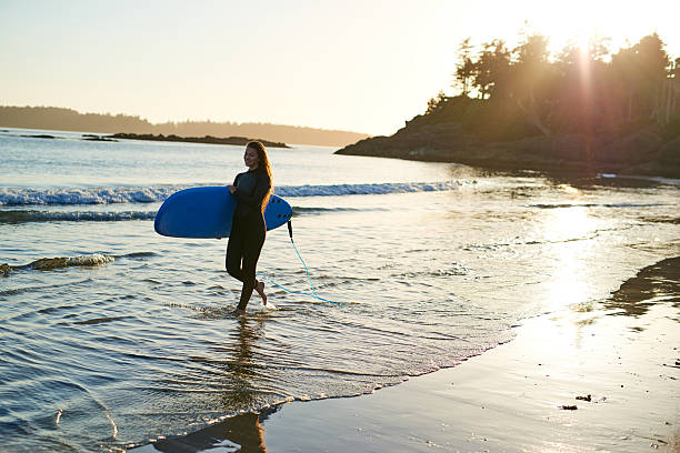 istock Strong beautiful young woman with surf on the beach 614335248