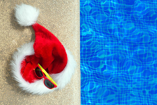 istock Red christmas hat and sunglasses near the pool. 614337636