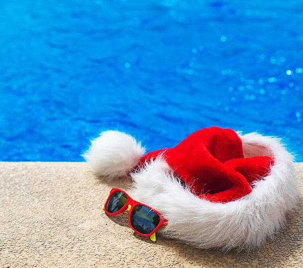 istock Red christmas hat and sunglasses near the pool. 614337704