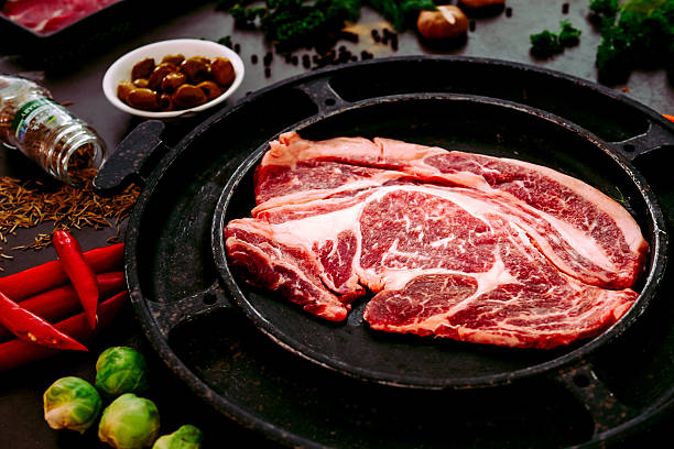 istock Raw uncooked beef rib eye steaks and spices on table 614338870