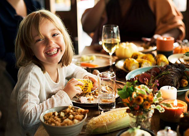 istock Little Girl Eating Corn Thanksgiving Celebration Concept 614339248