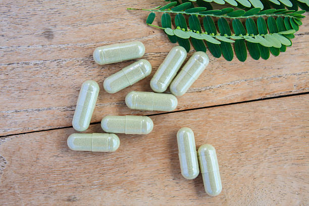 istock herbal capsules with green herbal leaf on wooden table 614339354