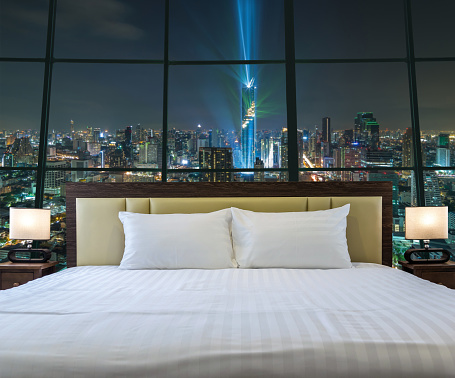 Luxury Interior bedroom with windows glass beside Top view of Bangkok Cityscape at night, Mahanakhon, relax and holiday concept, dicut each elements