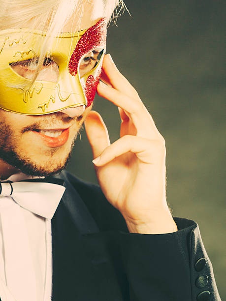 istock Young man in carnival mask on dark 614340140
