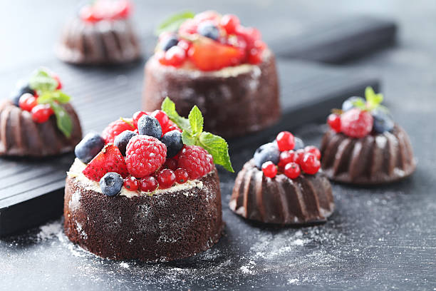 istock Sweet chocolate cakes with berries on black wooden table 614340300