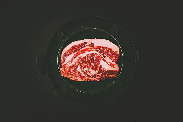 Raw uncooked beef rib eye steaks on table background