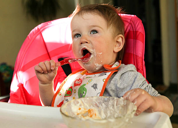istock Baby girl eats porridge 614340632