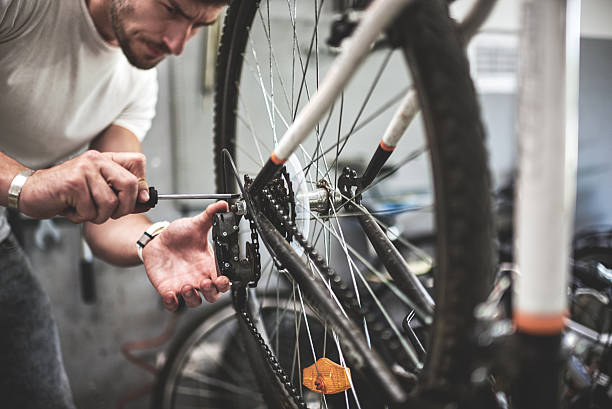 Mechanic repairing bicycle transmission Male mechanic inside bicycle store repairing the transmission mechanism on mountain bike. bicycle shop stock pictures, royalty-free photos & images