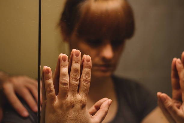 Mirror reflection of sad, depressed woman, with someone's hand on her shoulder