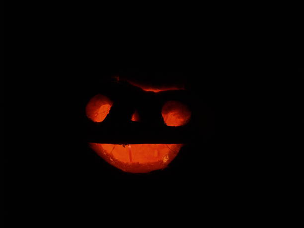 istock Scary Halloween pumpkins isolated on a black background.  glowing faces 614343610