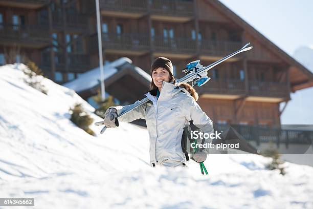 Woman Walking In The Snow Wearing Skis Stock Photo - Download Image Now - Carrying, Ski, Skiing