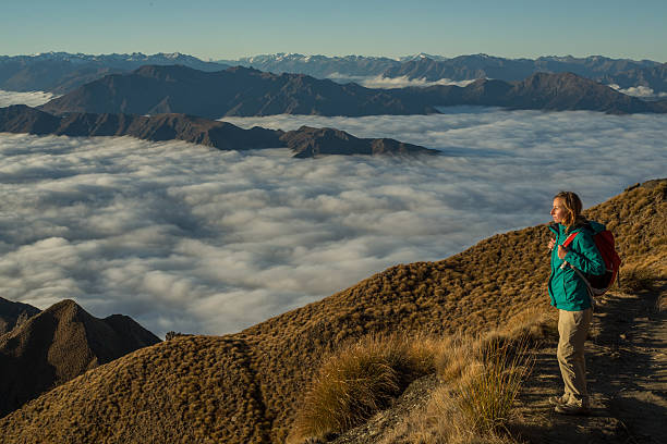 istock Hiker on mountain above cloud level looks at view 614346386