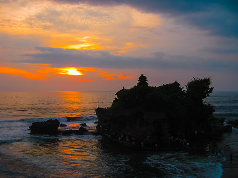 Tanah Lot and sea waves in golden sunset at Bali