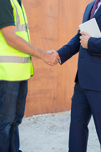 Businessman Shaking Hands With Builder On Construction Site
