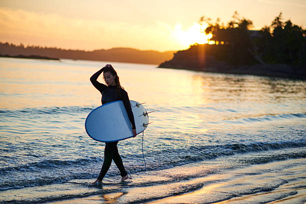 istock Strong beautiful young woman with surf on the beach 614403112
