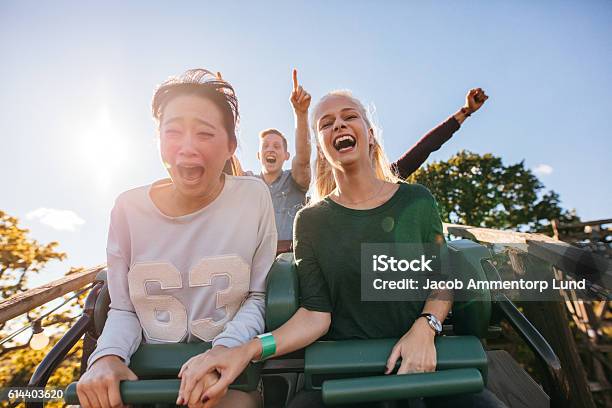 Enthusiastic Young Friends Riding Amusement Park Ride Stock Photo - Download Image Now