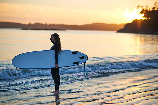 istock Strong beautiful young woman with surf on the beach 614403722