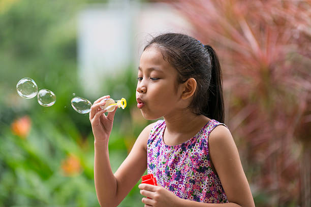 Asian school age girl play with bubble in a park,  Malay ethnicity, Singapore.