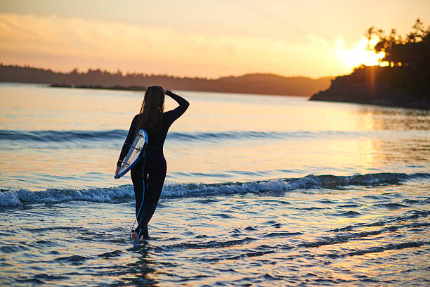 istock Strong beautiful young woman with surf on the beach 614404352