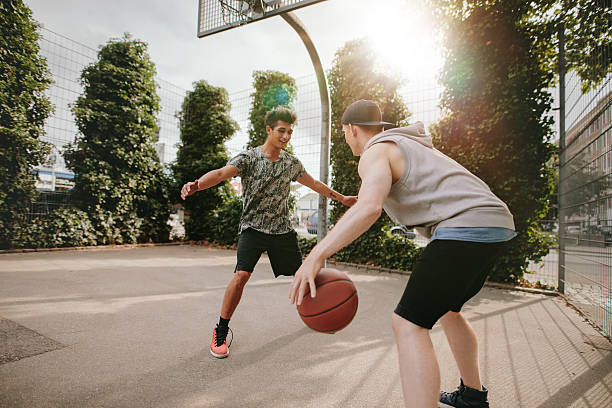 istock Young friends playing basketball together 614405460