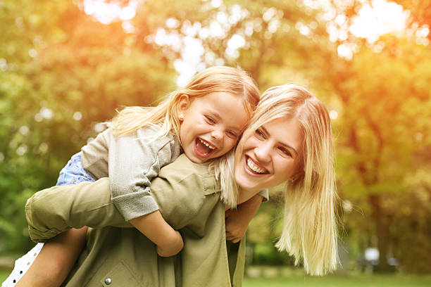 little girl on a piggy back ride with her mother. - formele tuin fotos stockfoto's en -beelden