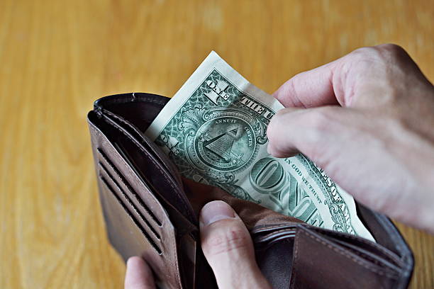 istock Male hands opening almost empty leather wallet with one Dollar 614407122
