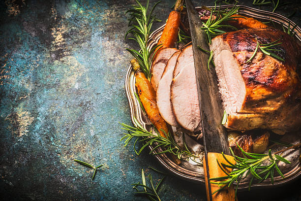 Roasted pork ham with kitchen knife and roast vegetables stock photo