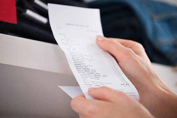 Beautiful young woman looking at the receipt from the grocery store at night. Close-up.