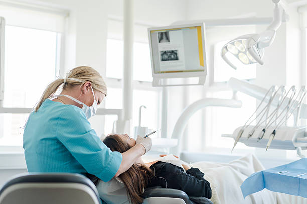 mujer dentista que examina a la mujer en la clínica - dentists chair dentist office dental hygiene clinic fotografías e imágenes de stock